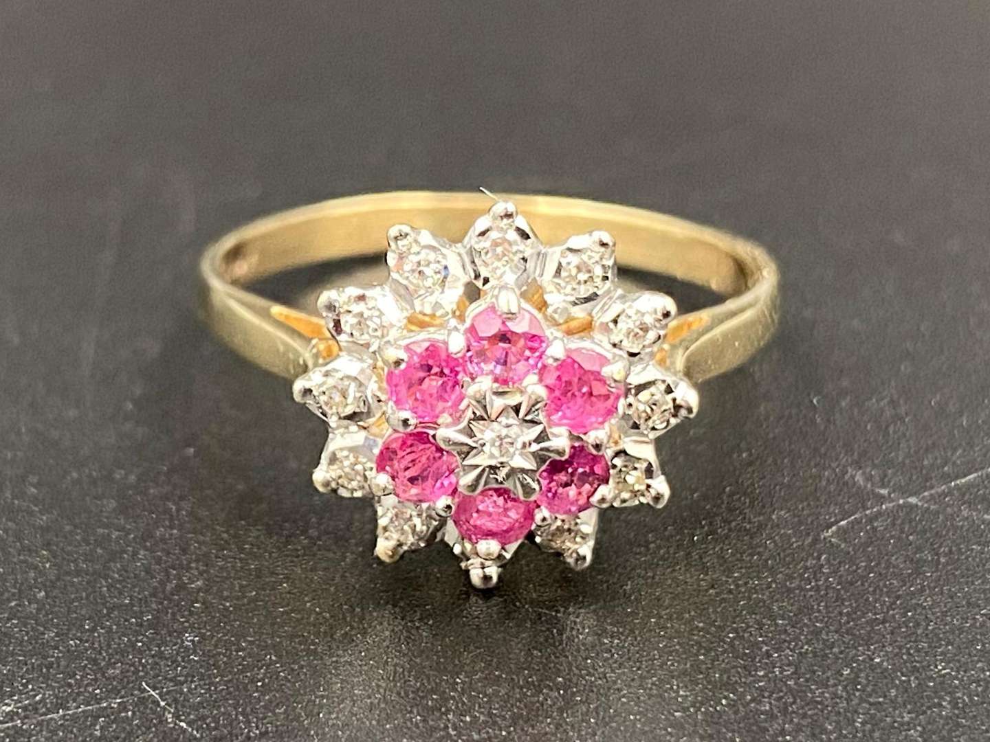 <p>A ruby and diamond flower head and 9ct yellow gold cluster ring.</p>